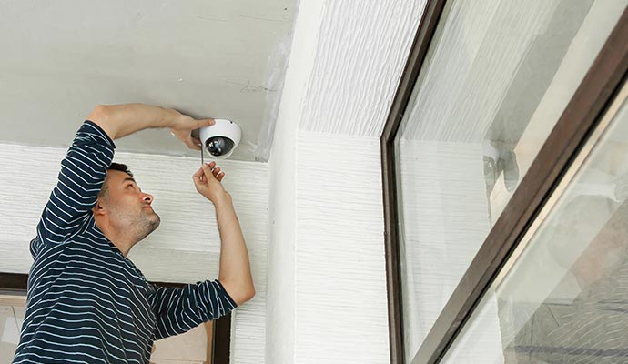 Person installing white CCTV on ceiling