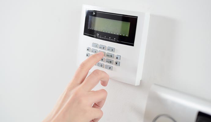 Hand entering code on white security keypad