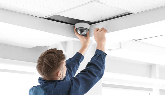 Technician Installing a Security Camera on a Building