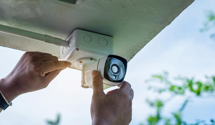 Technician installing white security camera.