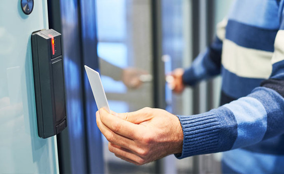 A man is using an access control key card to open a door.